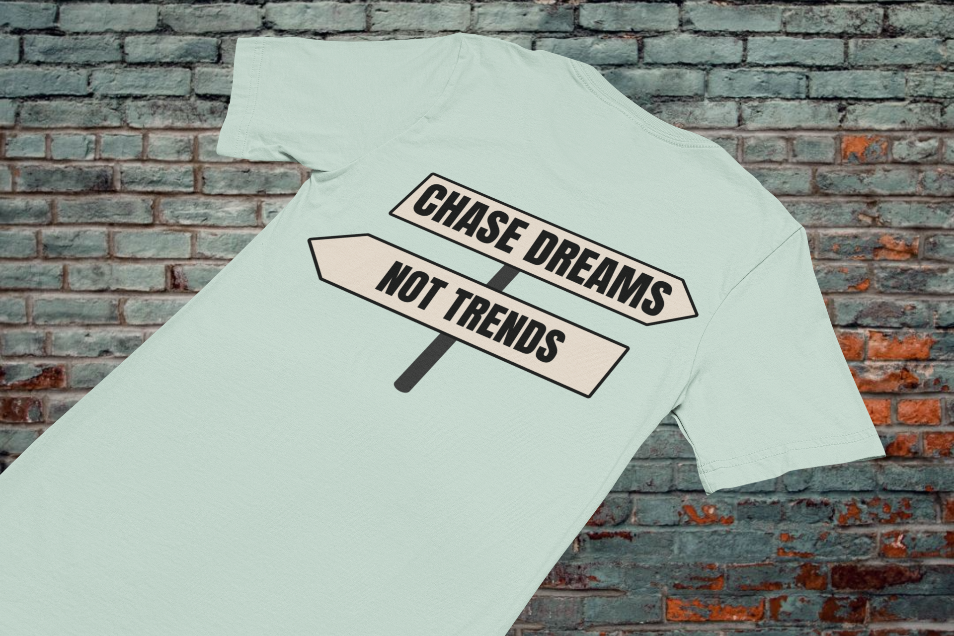 Chase Dreams Not Trends motivational t-shirt laid flat on brick background, minimalist design for modern creators.
