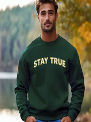 Man outdoors wearing Embroidered Stay True Sweatshirt in green.