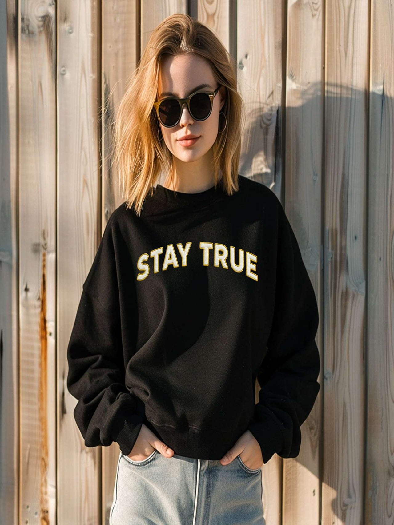 Woman posing in black Embroidered Stay True Sweatshirt with sunglasses.
