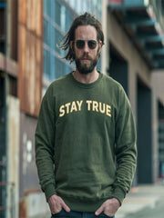 Man wearing Embroidered Stay True Sweatshirt in forest green outdoors.