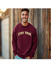 Man wearing Embroidered Stay True Sweatshirt in maroon, smiling outdoors.