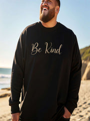 Man at the beach wearing black Embroidered Kindness Sweatshirt casual style.