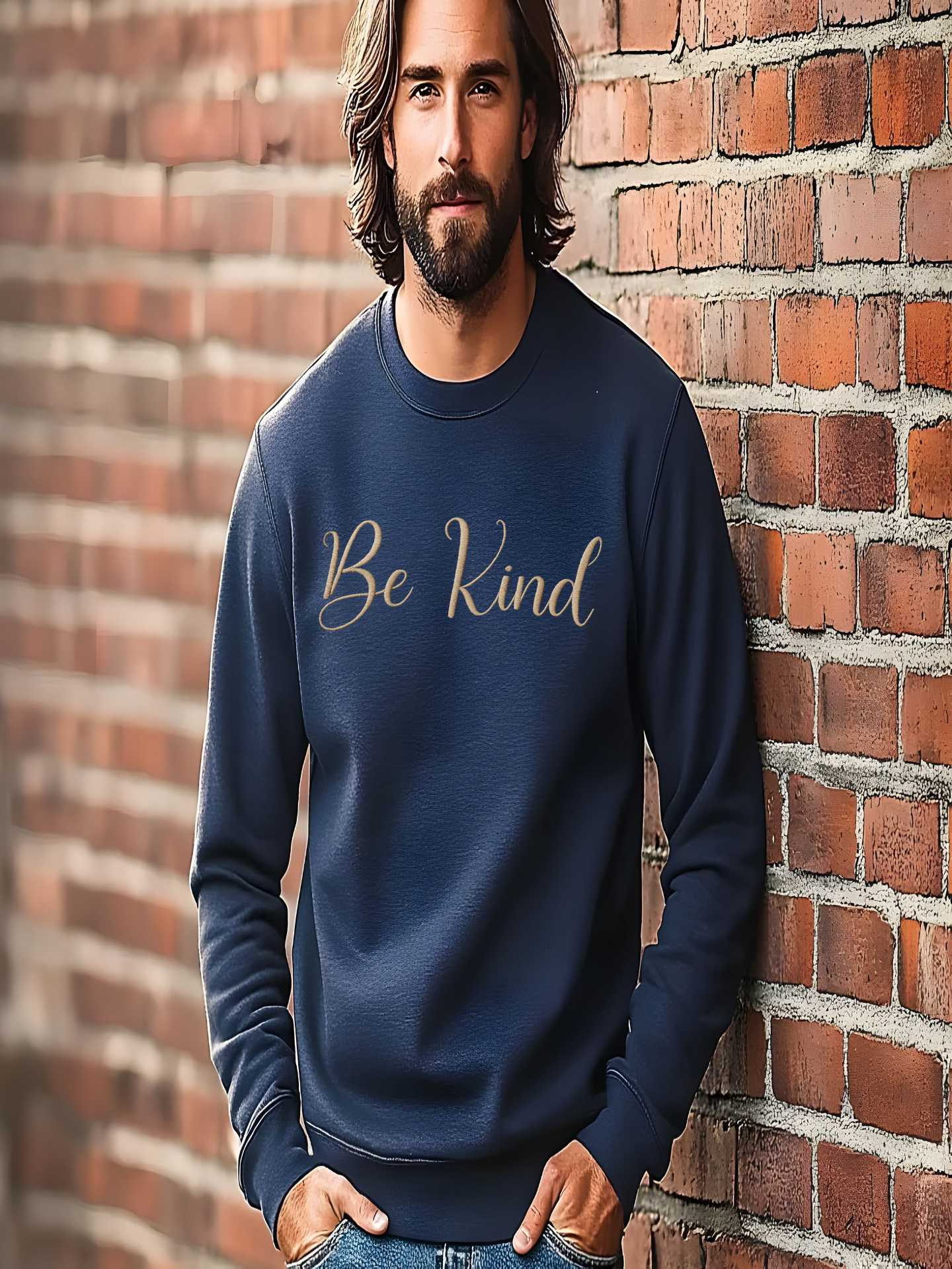 Man posing against brick wall in navy Embroidered Kindness Sweatshirt