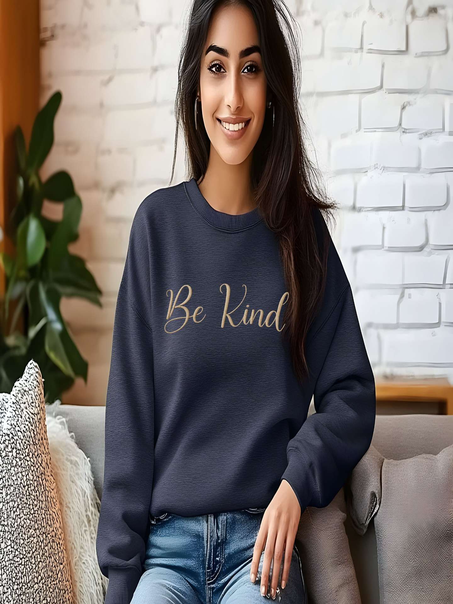 Woman sitting indoors with gray Embroidered Kindness Sweatshirt relaxed look.
