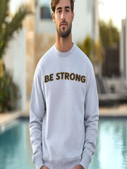 Embroidered Motivational Sweatshirt featuring "BE STRONG" text worn by a model near a pool.