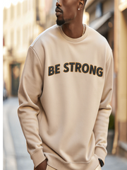 Embroidered Motivational Sweatshirt featuring 'BE STRONG' design worn by a man in a stylish outdoor setting.
