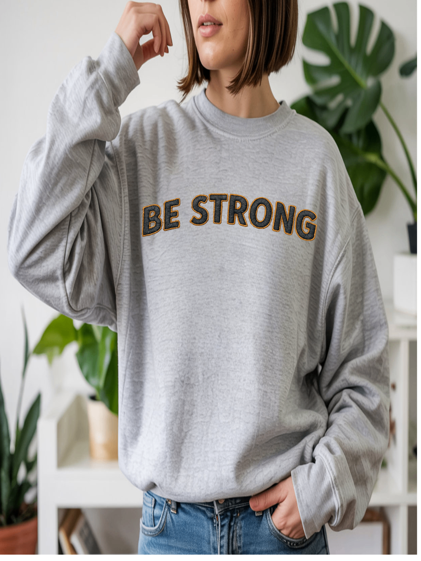 Embroidered Motivational Sweatshirt featuring the phrase 'BE STRONG' on a gray background, perfect for casual wear.