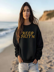 Woman on the beach wearing Embroidered Keep Faith Sweatshirt in black