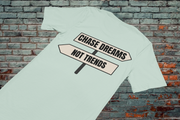 Chase Dreams T-Shirt flat lay on rustic surface with brick wall background