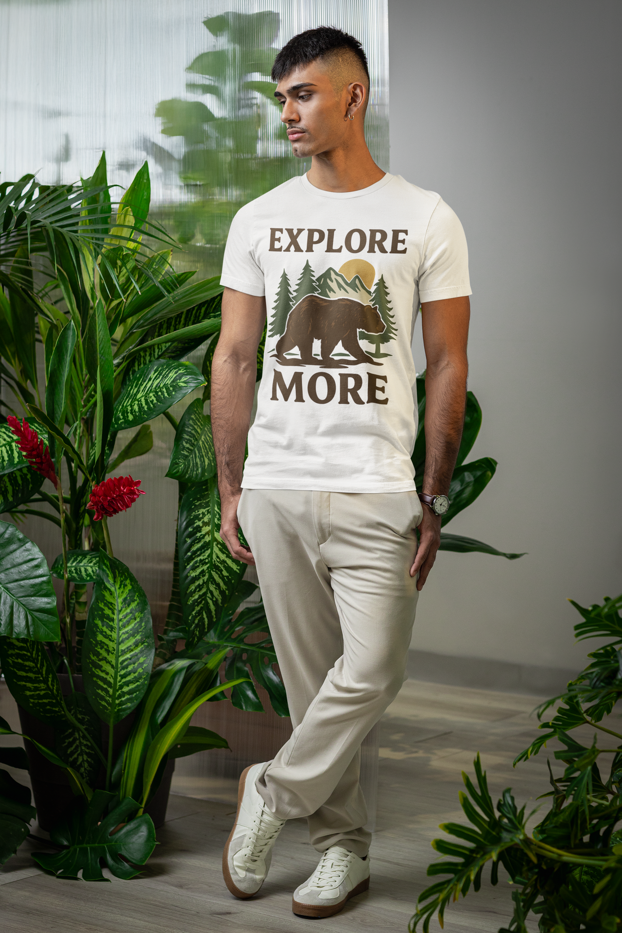 Man wearing Explore More t-shirt standing confidently among lush green plants