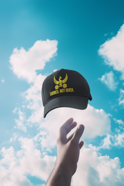 Embroidered Dad Hat Earned Not Given – Black cap with golden embroidered design held up against the sky.