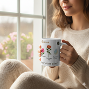 Floral Ceramic Mug Bloom In Your Own Time held by a woman in a cozy sweater by a window with floral designs.