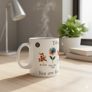 A Floral Ceramic Mug Bloom In Your Own Time featuring motivational phrases and floral designs, with steam rising from a hot drink.