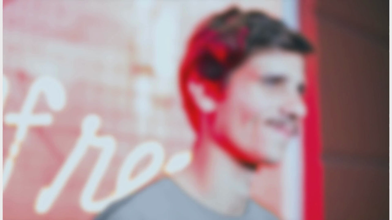 A young man wearing a t-shirt that says “Chase Dreams Not Trends” stands in front of a neon-lit café. The video promotes a motivational and stylish apparel collection from Grya Prints, focusing on purposeful design and self-expression.